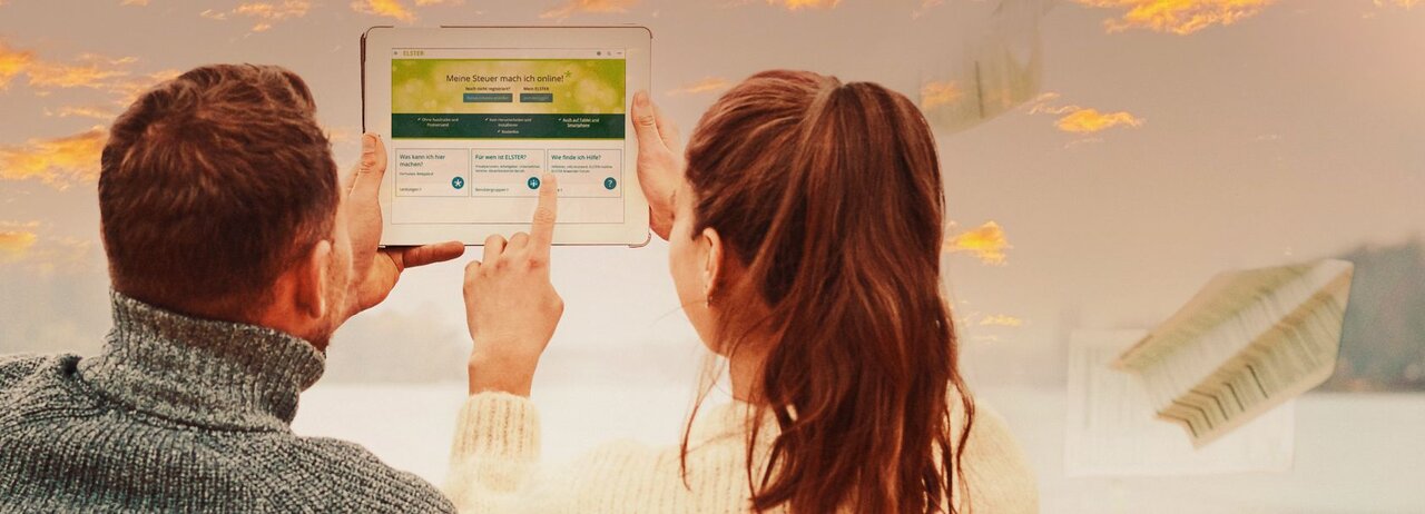 Zwei Personen sitzen am Strand und nutzen die ELSTER-Seiten auf dem Tablet.